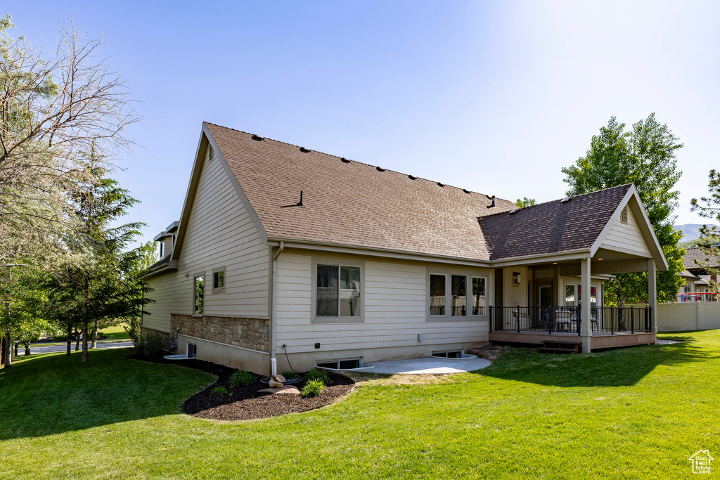 Rear view of house with a patio, a yard, and a shingled roof