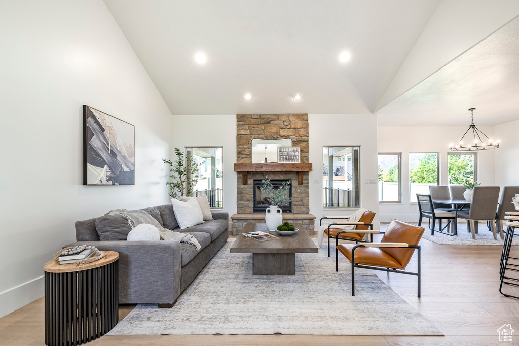 Living area featuring a chandelier, light wood-style floors, a fireplace, recessed lighting, and high vaulted ceiling