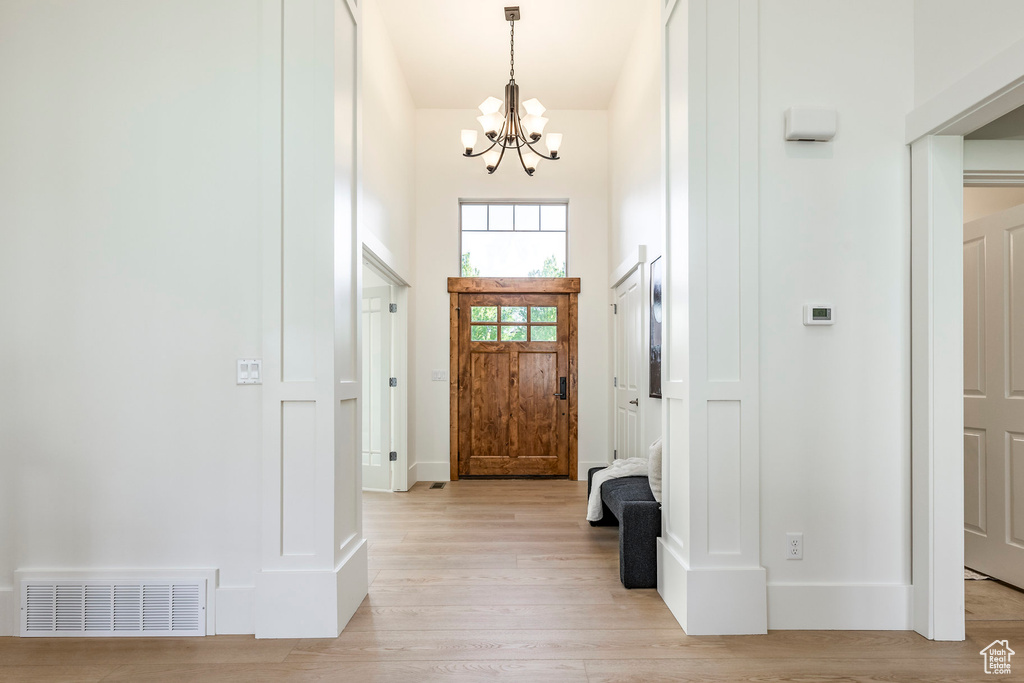 Foyer with a chandelier, light wood-type flooring, and baseboards