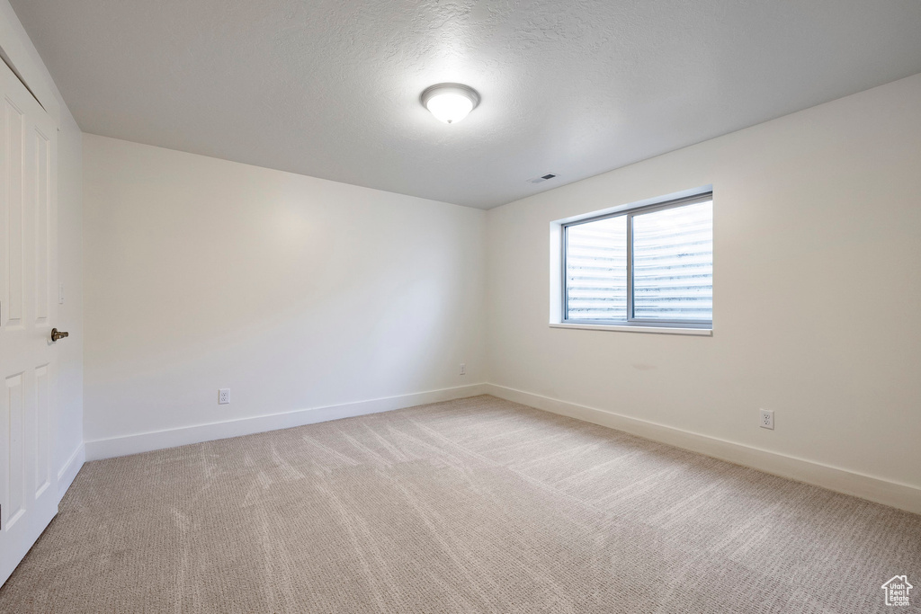 Spare room featuring light colored carpet and baseboards