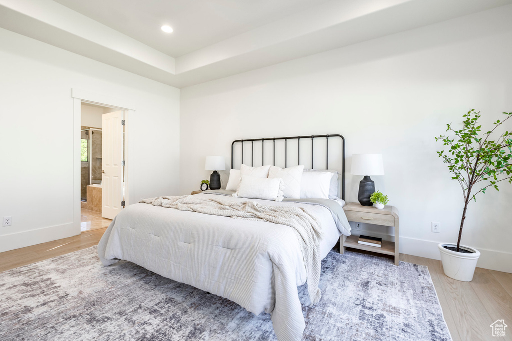Bedroom featuring wood finished floors, baseboards, recessed lighting, and connected bathroom