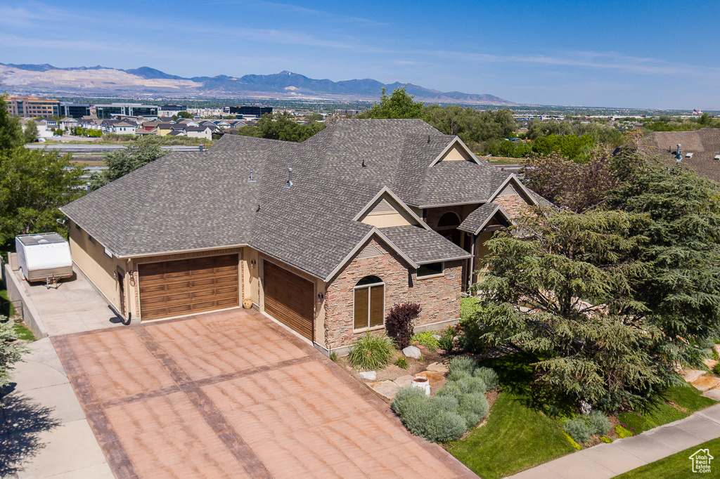 View of front of house featuring a garage, roof with shingles, stone siding, and concrete driveway