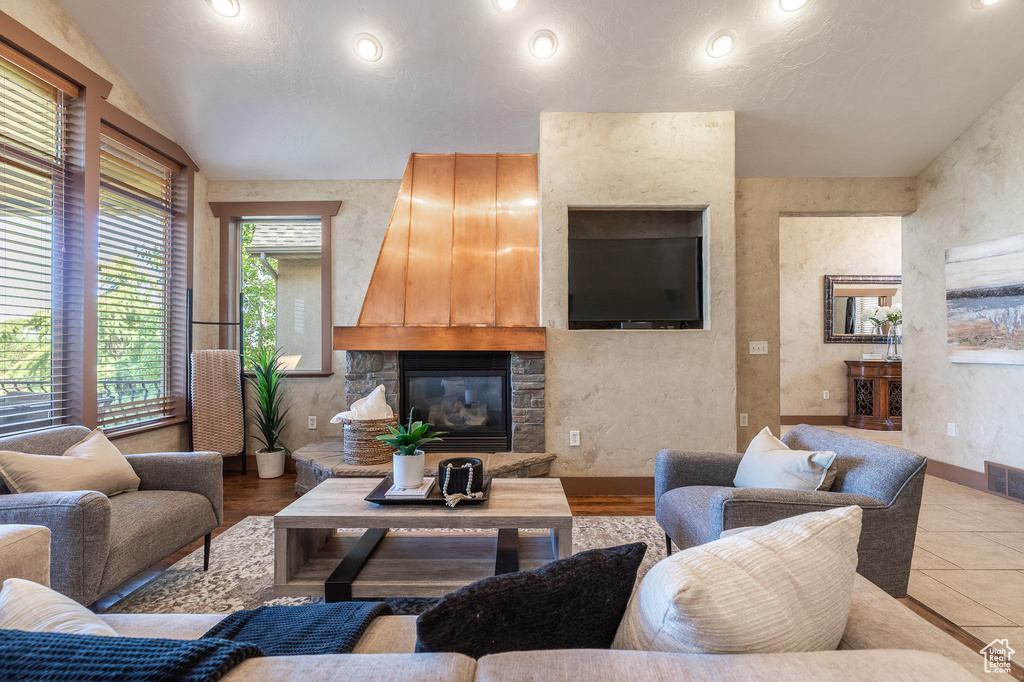 Living area with a stone fireplace, recessed lighting, and vaulted ceiling
