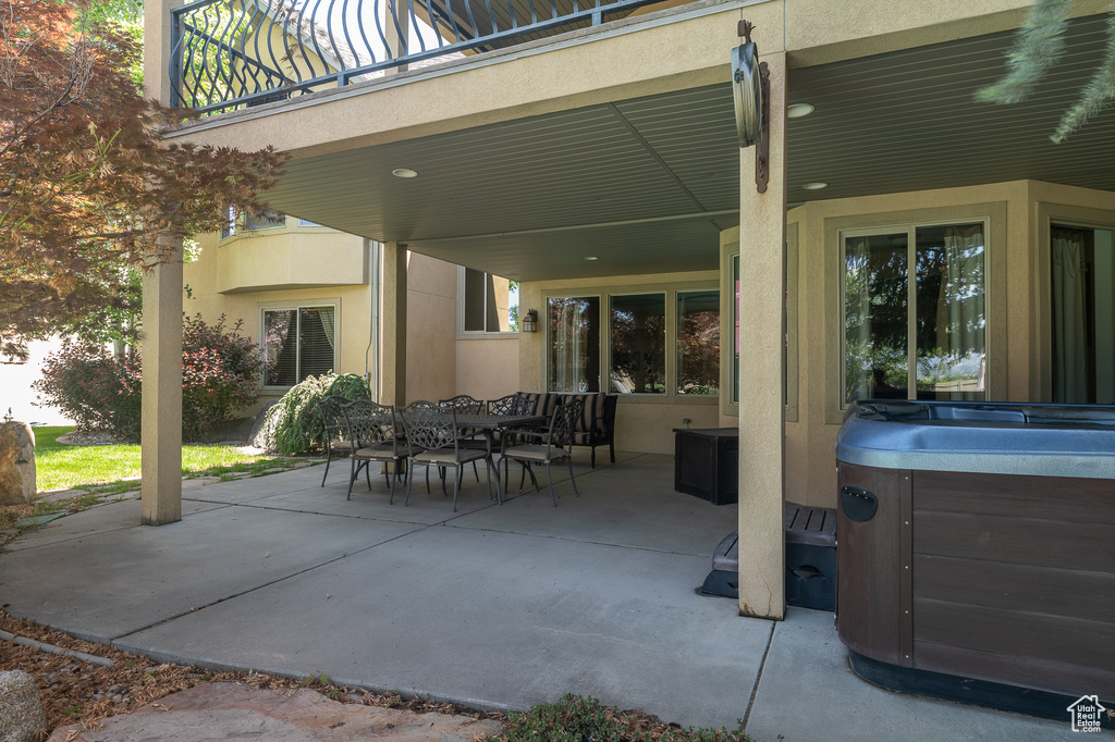View of patio / terrace featuring a hot tub, a balcony, and outdoor dining space