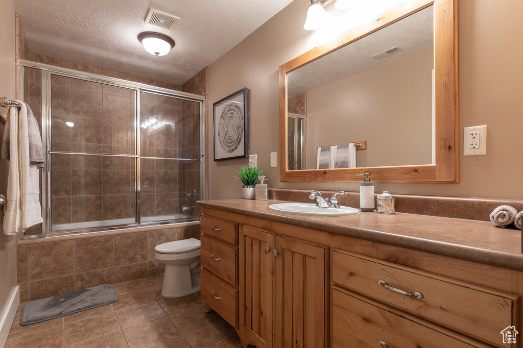 Bathroom with vanity, tiled shower / bath combo, tile patterned flooring, and toilet