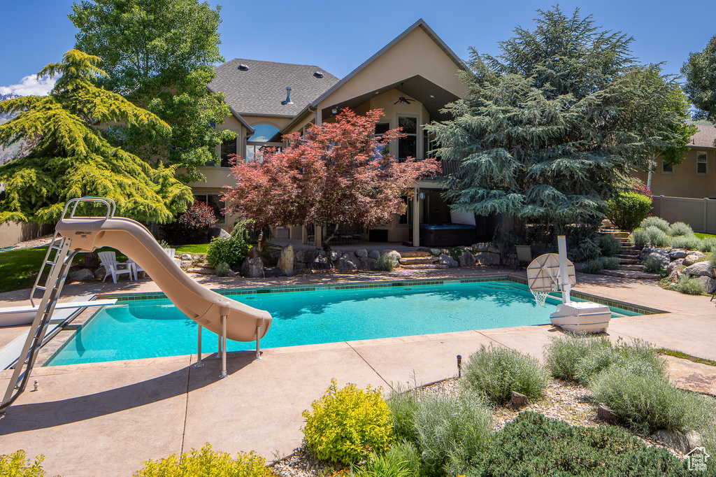 Outdoor pool featuring a water slide, a patio, and a diving board