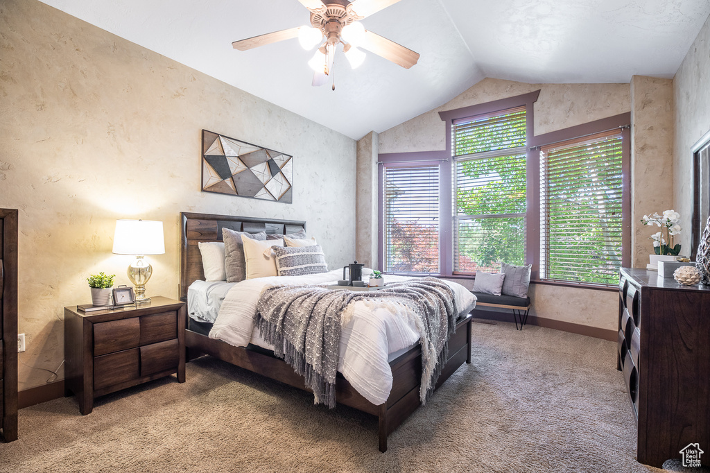 Bedroom with multiple windows, vaulted ceiling, light carpet, baseboards, and ceiling fan