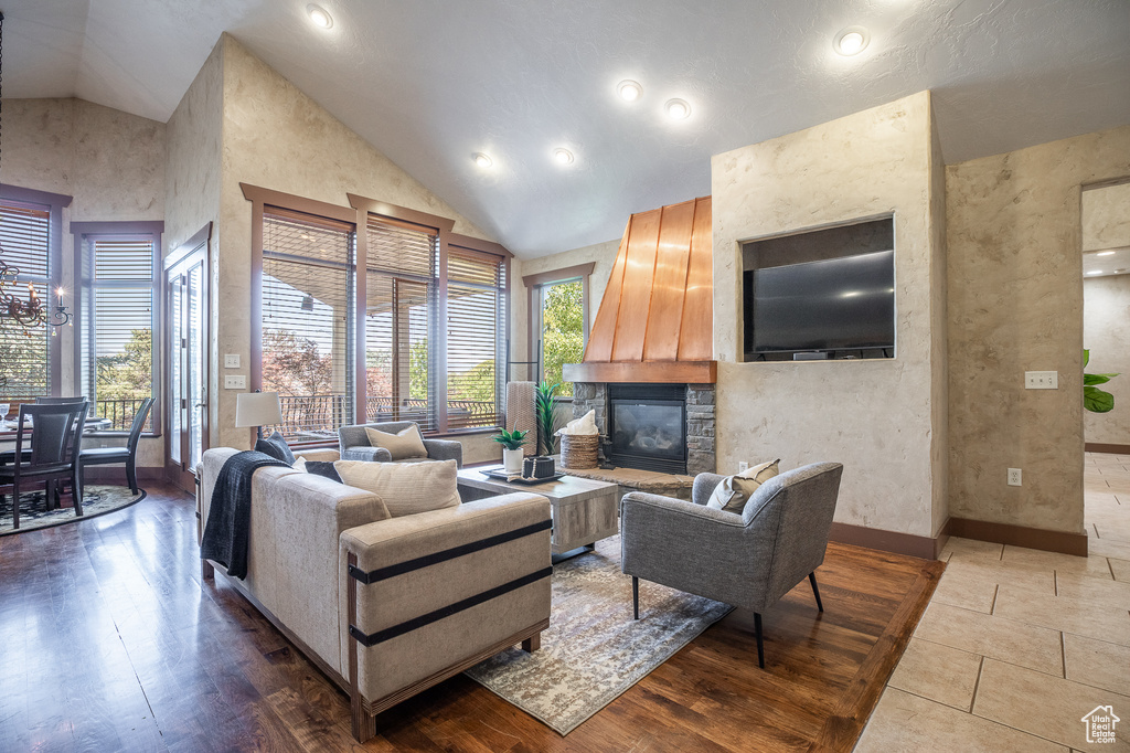 Living room with a stone fireplace, high vaulted ceiling, baseboards, and recessed lighting