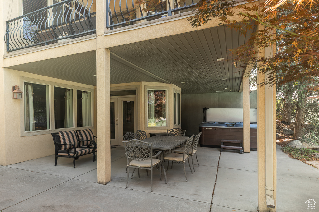 View of patio / terrace featuring a hot tub, french doors, a balcony, and outdoor dining space