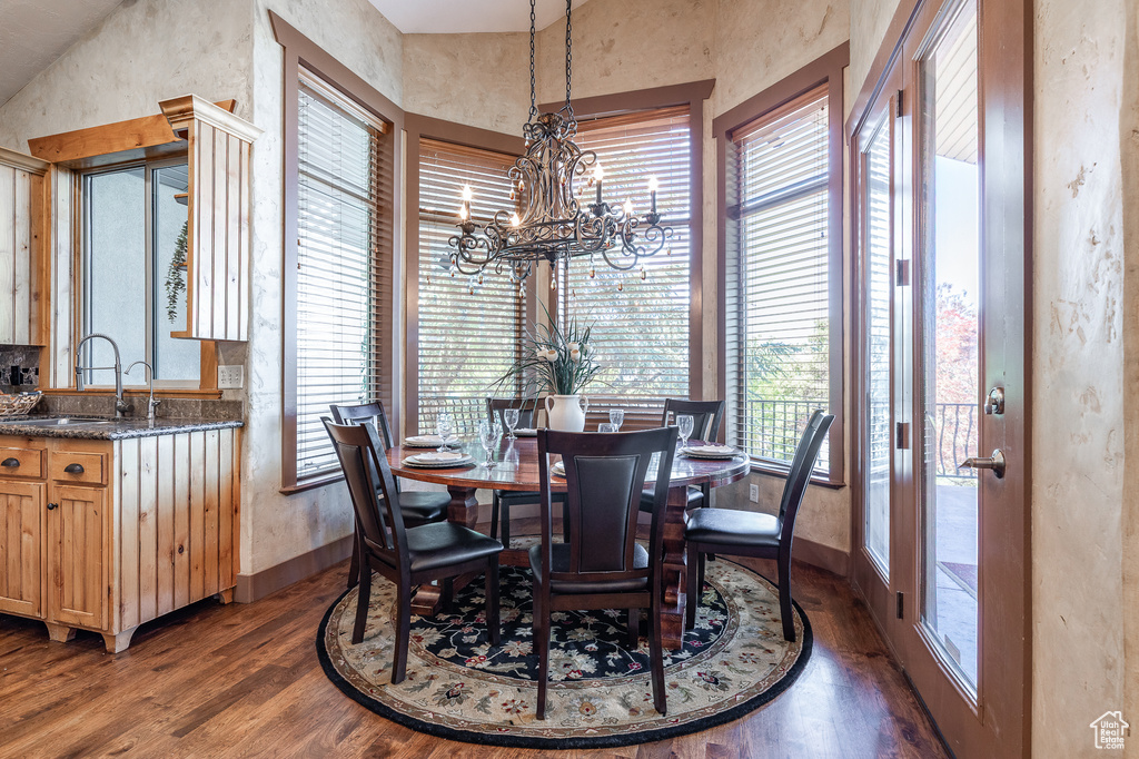 Dining space with wood finished floors, a chandelier, and baseboards