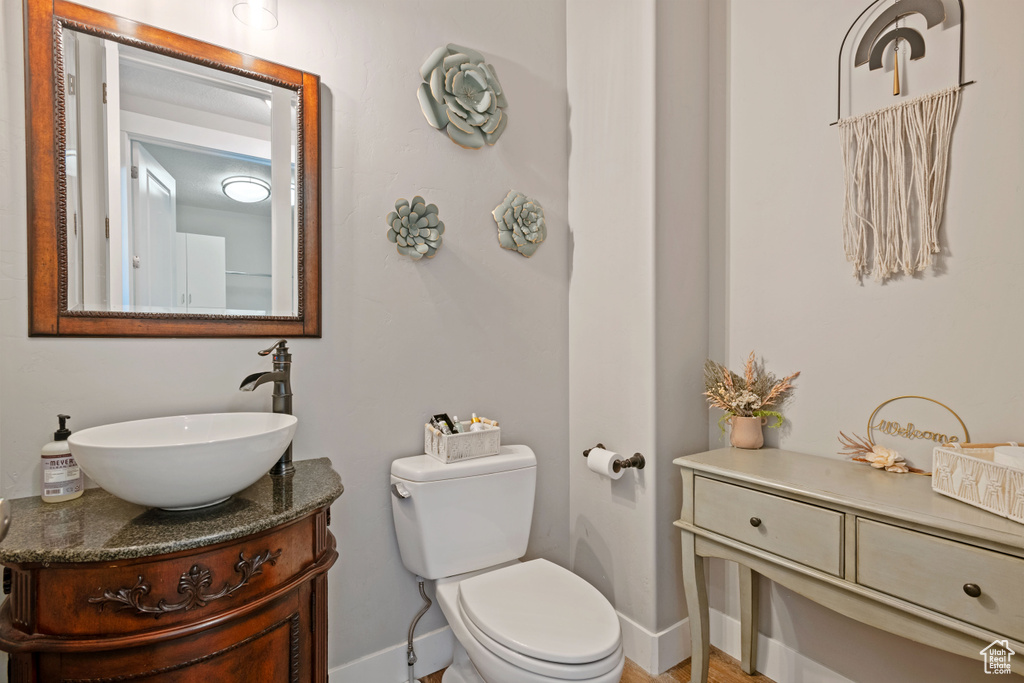 Half bathroom featuring baseboards, vanity, and toilet
