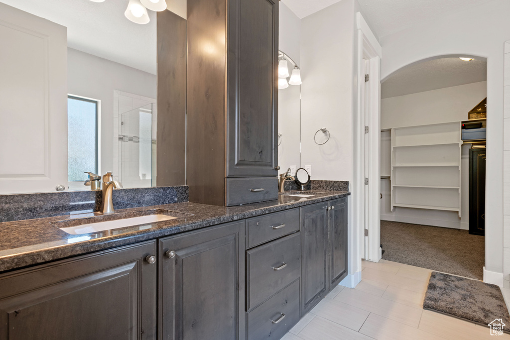 Bathroom with double vanity, a shower stall, and a spacious closet