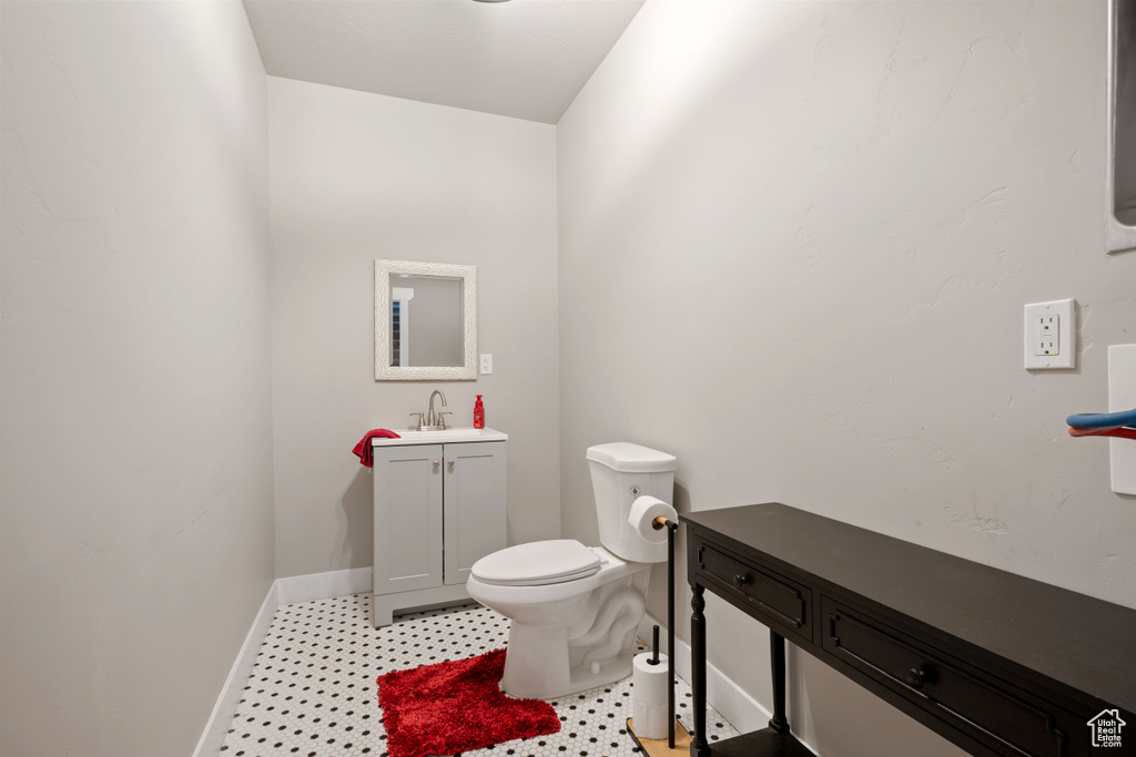 Bathroom featuring baseboards, toilet, vanity, and tile patterned floors