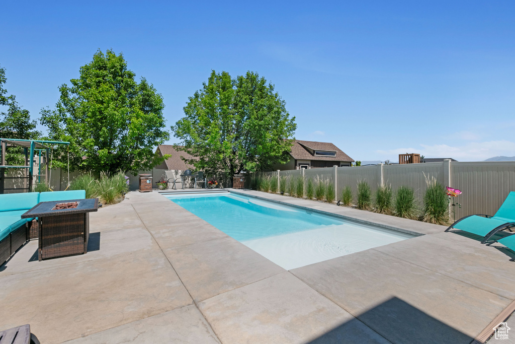 View of pool with a patio area, a fenced backyard, and a fire pit