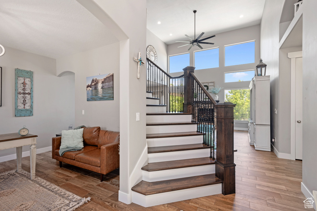 Staircase with arched walkways, a ceiling fan, wood finished floors, baseboards, and recessed lighting