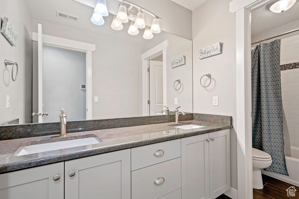 Bathroom with double vanity, toilet, and shower / tub combo