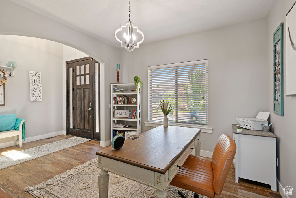 Office area featuring arched walkways, a chandelier, wood finished floors, and baseboards