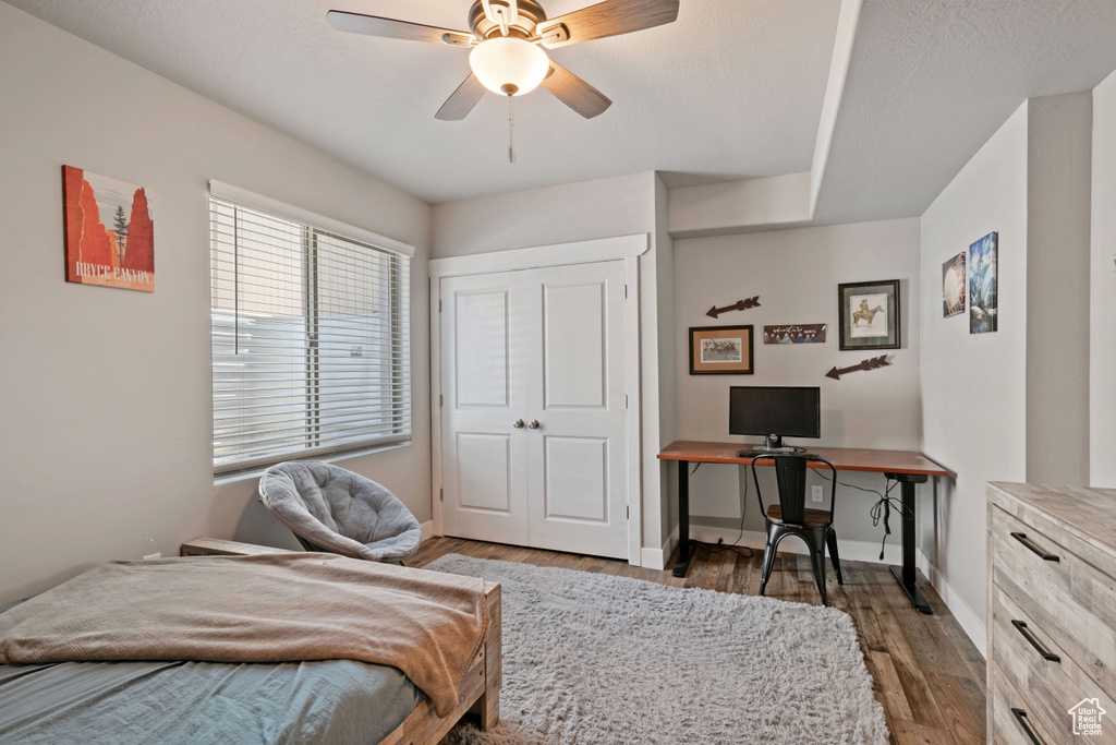 Bedroom with wood finished floors, baseboards, a ceiling fan, and an office area