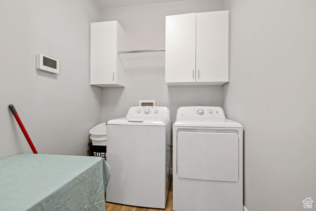Laundry area featuring cabinet space, washing machine and dryer, and light wood-type flooring