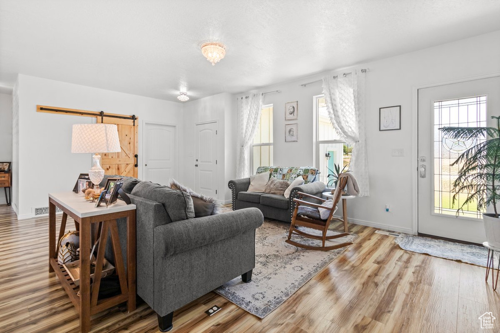 Living room with a barn door, wood finished floors, and baseboards
