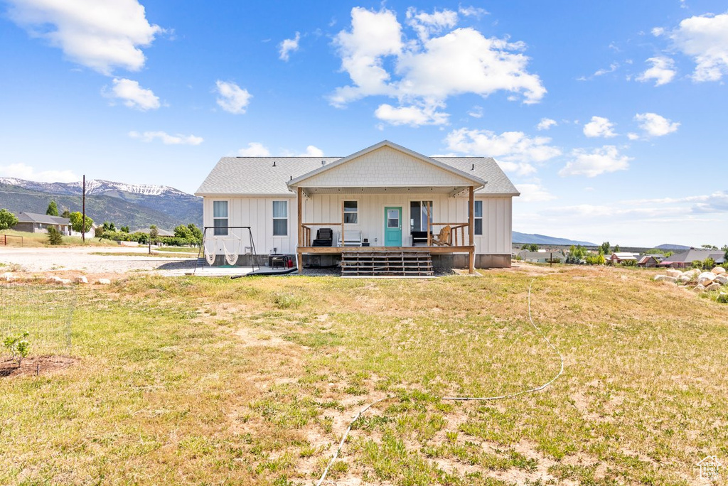 Rear view of house with a mountain view, board and batten siding, and a yard
