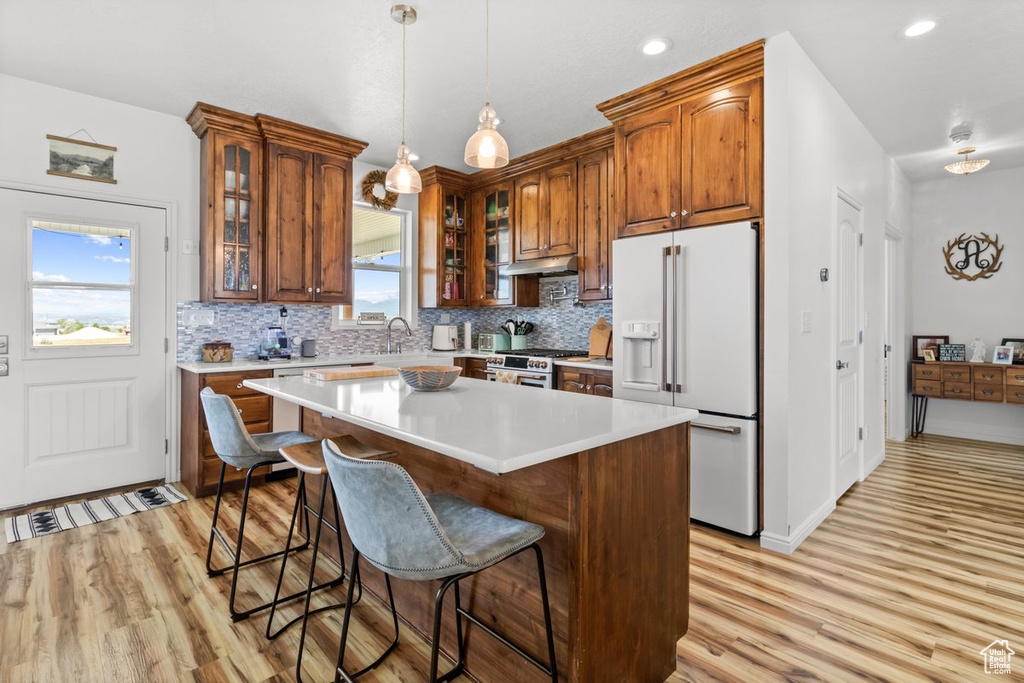 Kitchen with high quality appliances, light wood-style flooring, tasteful backsplash, a kitchen bar, and recessed lighting
