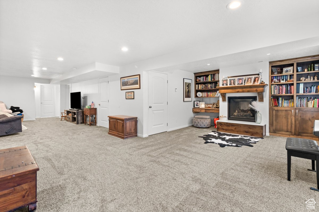 Carpeted living area featuring a glass covered fireplace, recessed lighting, and baseboards