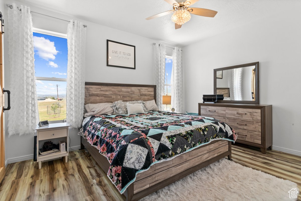 Bedroom featuring wood finished floors, multiple windows, and baseboards