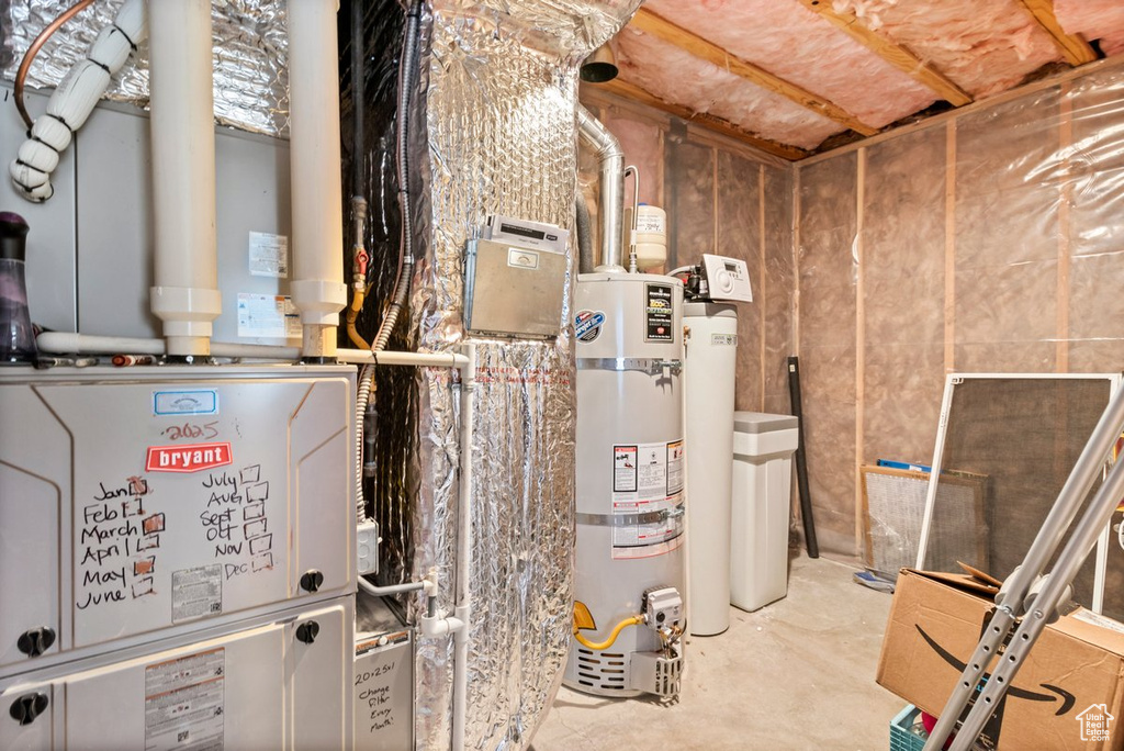 Utility room featuring strapped water heater and heating unit