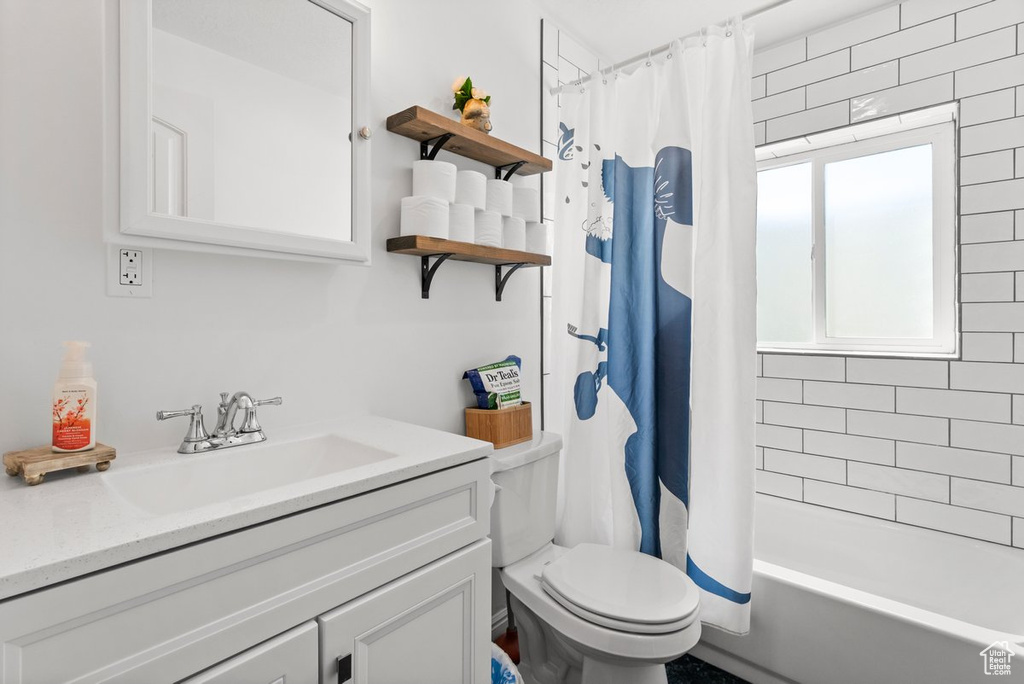 Bathroom featuring vanity, toilet, and shower / bath combination with curtain