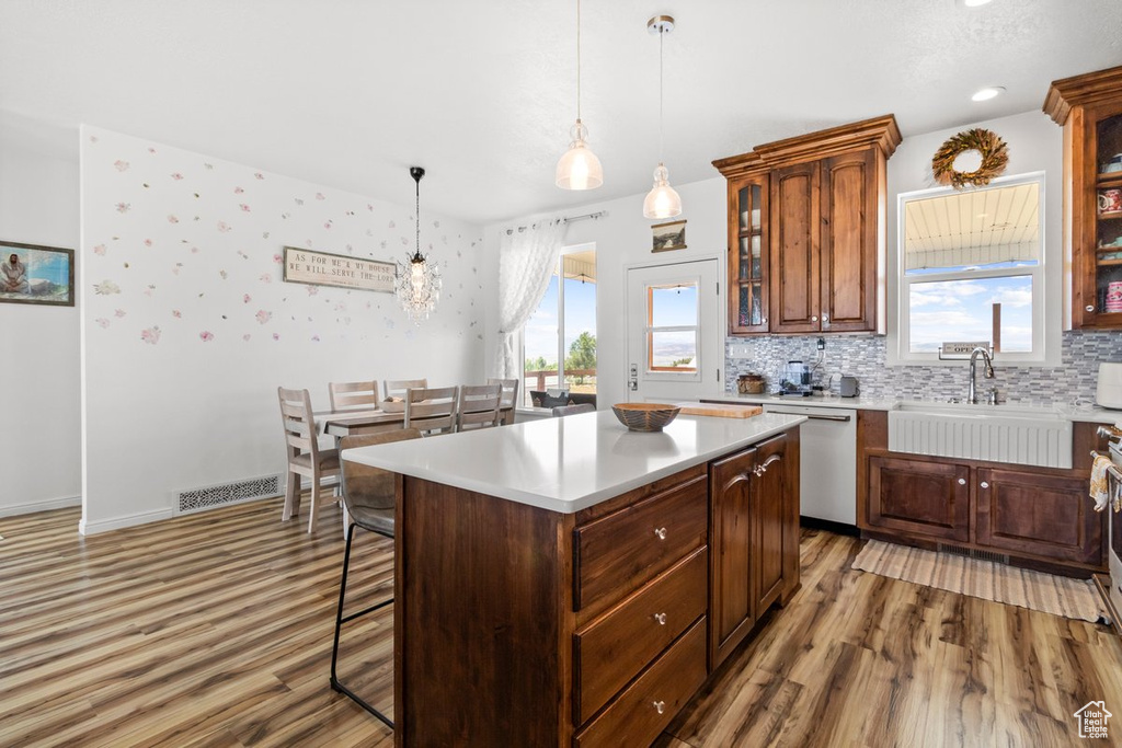 Kitchen with dishwasher, a sink, light wood-style floors, and healthy amount of natural light
