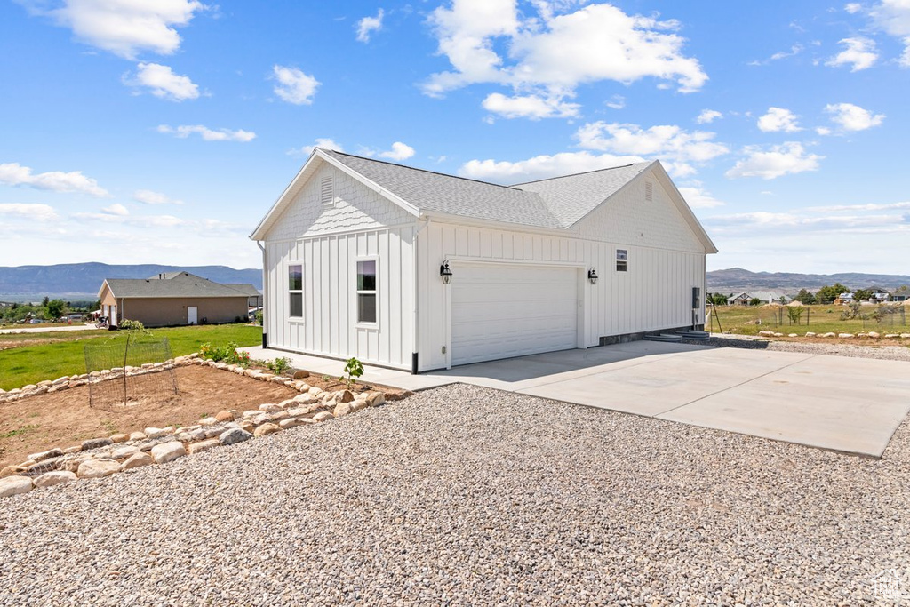 View of property exterior with a mountain view, board and batten siding, a garage, and driveway