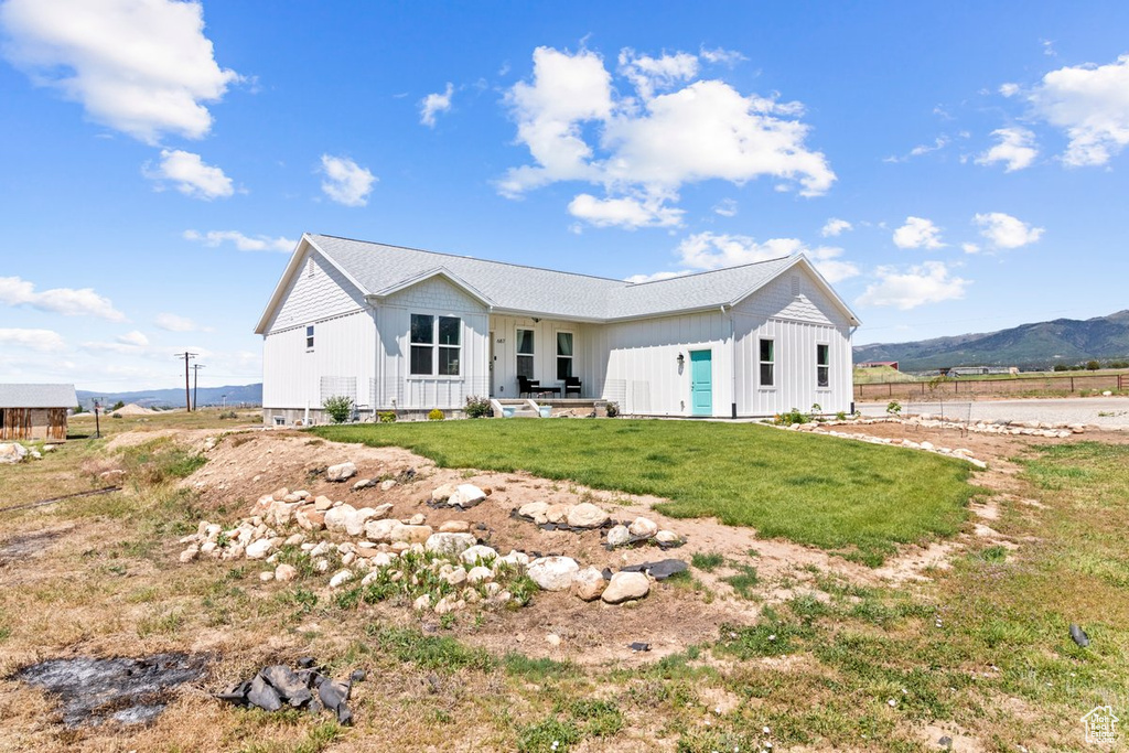Back of property with board and batten siding, a lawn, and a mountain view
