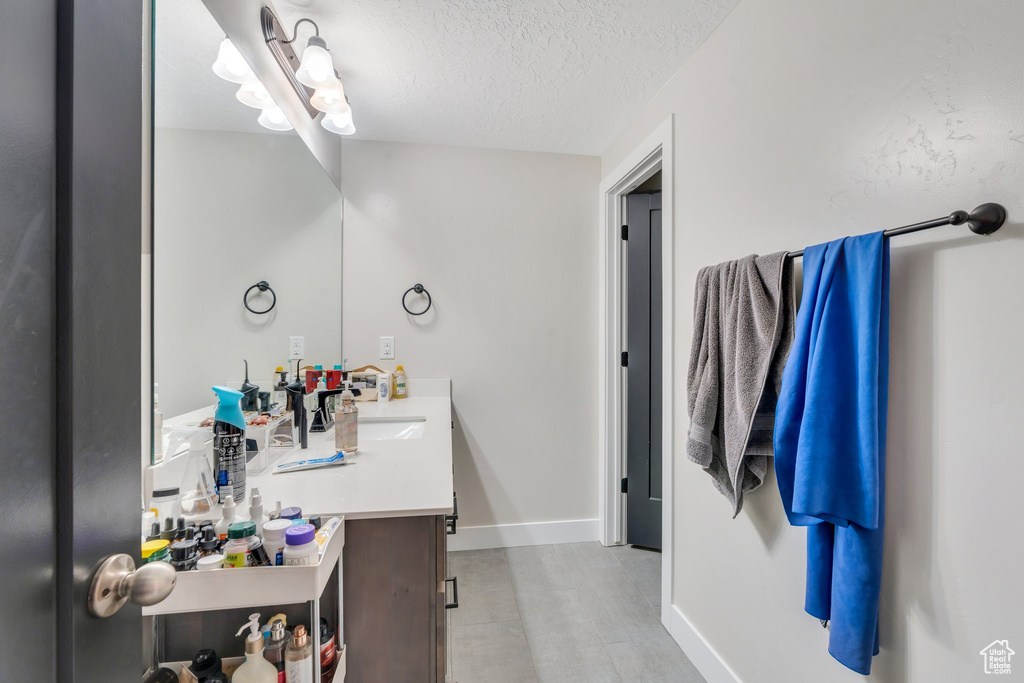 Bathroom with vanity, a textured ceiling, and baseboards