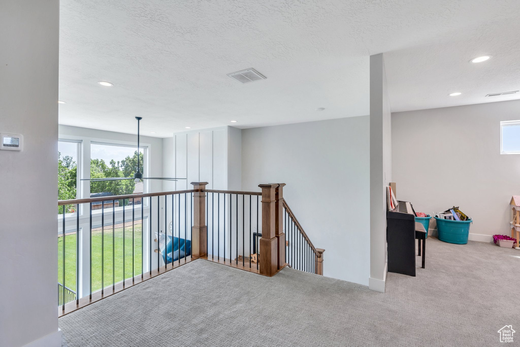 Corridor with carpet, recessed lighting, baseboards, a textured ceiling, and an upstairs landing