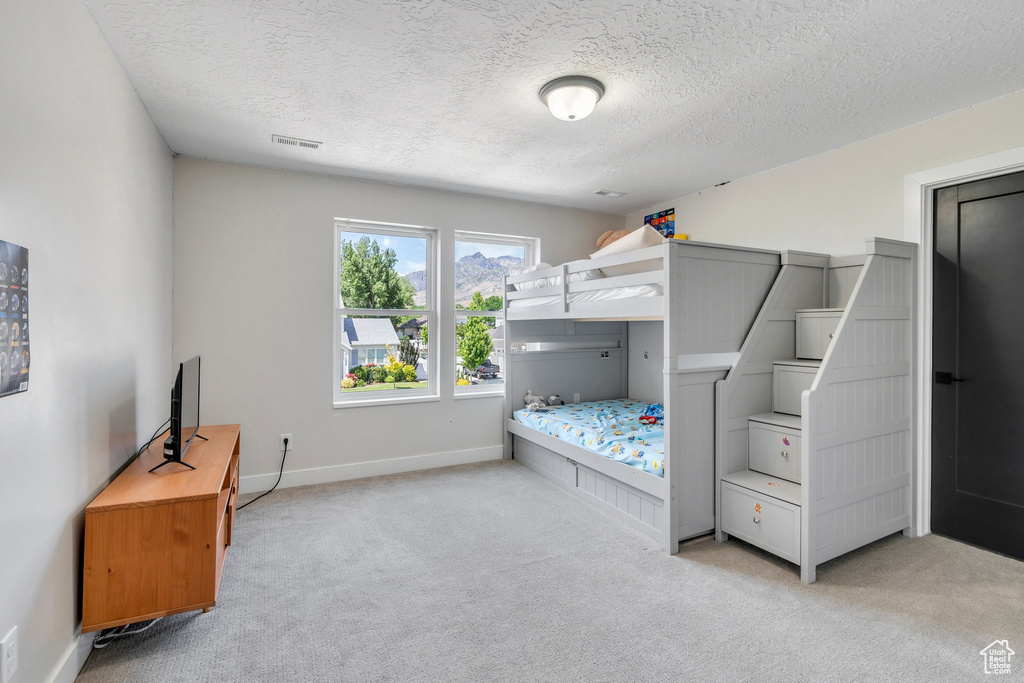Bedroom featuring light colored carpet, a textured ceiling, and baseboards