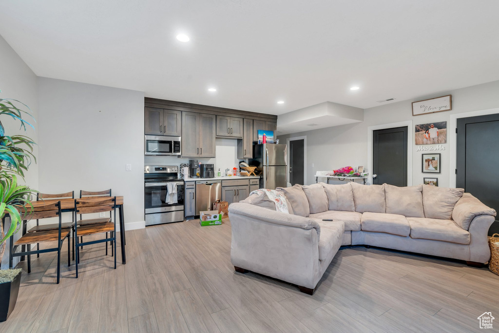 Living room with light wood-style flooring, recessed lighting, and baseboards