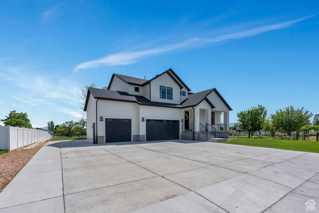 Modern inspired farmhouse with concrete driveway, a porch, and a garage