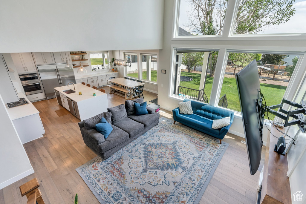 Living area with a high ceiling, healthy amount of natural light, light wood-style flooring, and baseboards