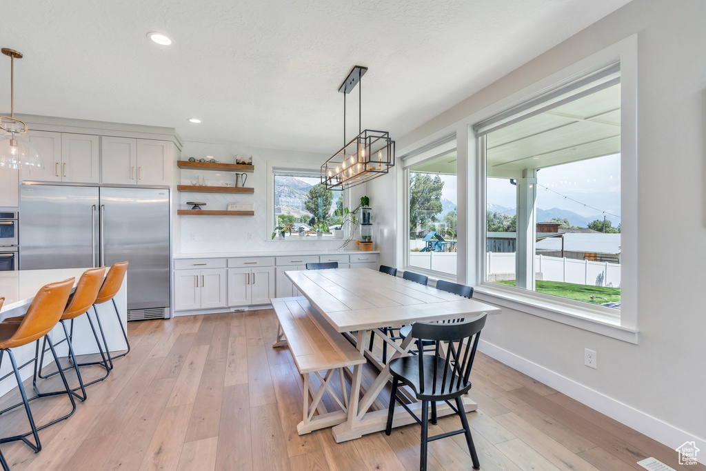 Dining room with light wood finished floors, baseboards, recessed lighting, and a chandelier