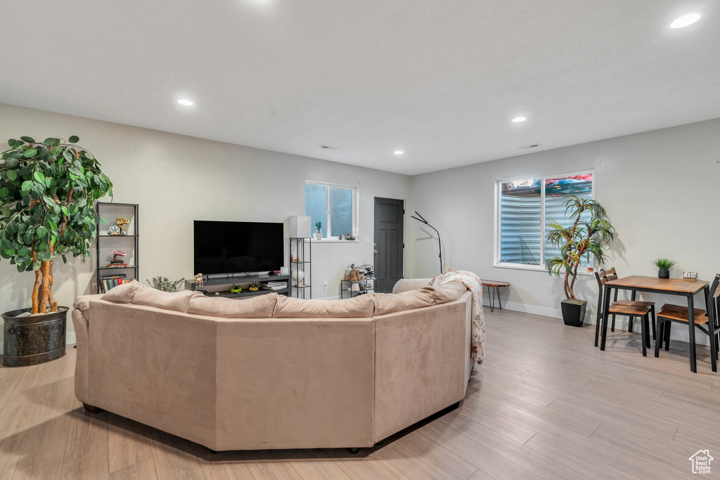 Living area featuring recessed lighting, baseboards, light wood-type flooring, and healthy amount of natural light
