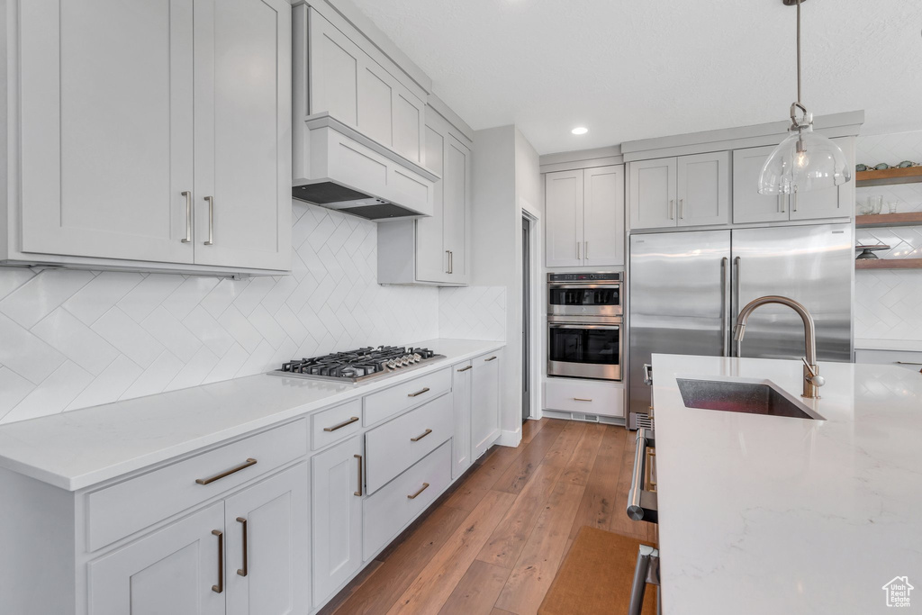 Kitchen with stainless steel appliances, a sink, open shelves, tasteful backsplash, and recessed lighting