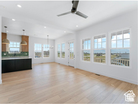 Unfurnished living room featuring a chandelier, light wood-type flooring, ceiling fan, and recessed lighting