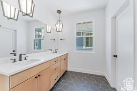 Bathroom with plenty of natural light, double vanity, tile patterned flooring, and baseboards