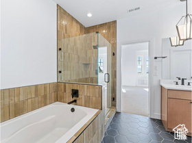 Full bathroom featuring vanity, a bath, a stall shower, tile patterned floors, and recessed lighting