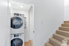 Washroom featuring stacked washer / dryer and wood finished floors