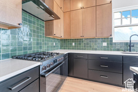 Kitchen featuring stainless steel range, range hood, a sink, and light countertops
