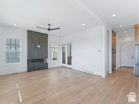 Unfurnished living room with ceiling fan, a large fireplace, light wood-type flooring, and recessed lighting