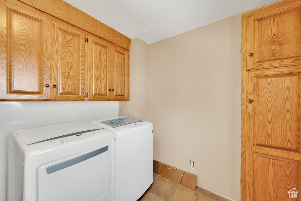 Washroom featuring separate washer and dryer, cabinet space, baseboards, and tile patterned floors