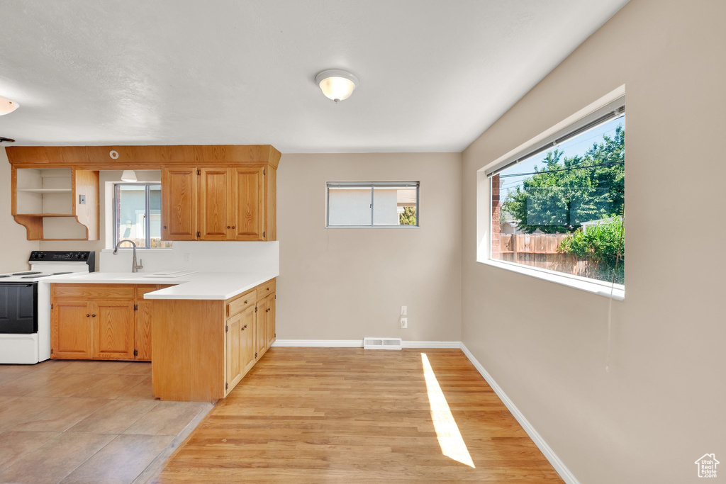 Kitchen featuring white electric range oven, a peninsula, light countertops, baseboards, and open shelves